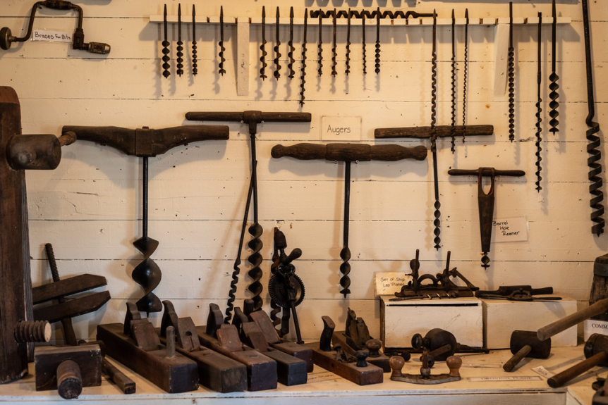 How to Identify Old Antique Tools. Old tools hanging on a wall, including hammers, augers, chisels, and saws. This image can be used to identify old tools, learn about antique tools, or simply appreciate the craftsmanship of these tools.